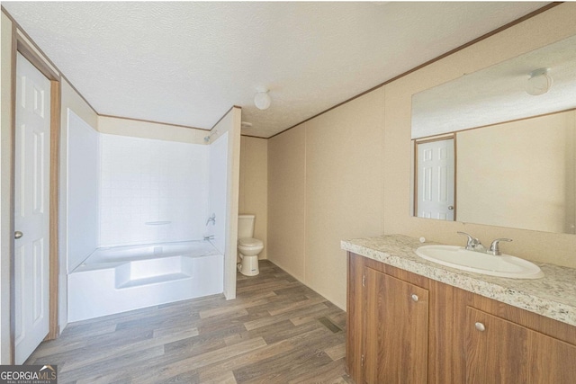 full bath featuring toilet, ornamental molding, a textured ceiling, vanity, and wood finished floors