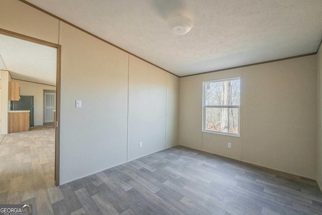 spare room with ornamental molding and wood finished floors