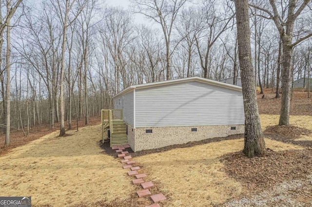 view of side of property with crawl space and stairs