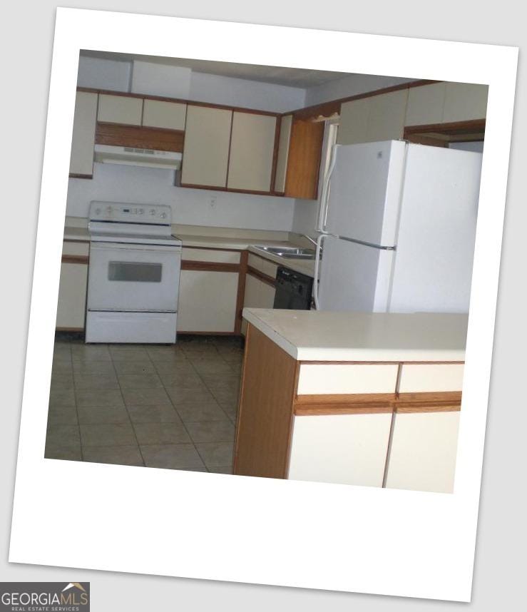 kitchen with light countertops, a sink, white appliances, under cabinet range hood, and tile patterned floors