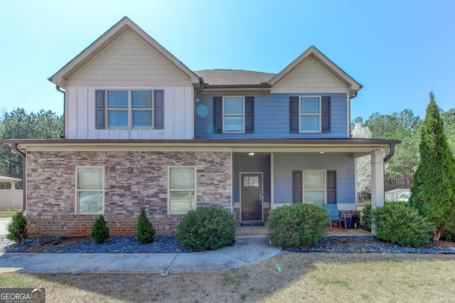 view of front of house with stone siding, covered porch, and board and batten siding