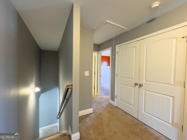 hall with carpet floors, attic access, baseboards, and an upstairs landing