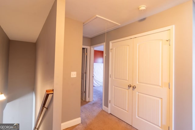 hallway with baseboards, an upstairs landing, attic access, and light colored carpet