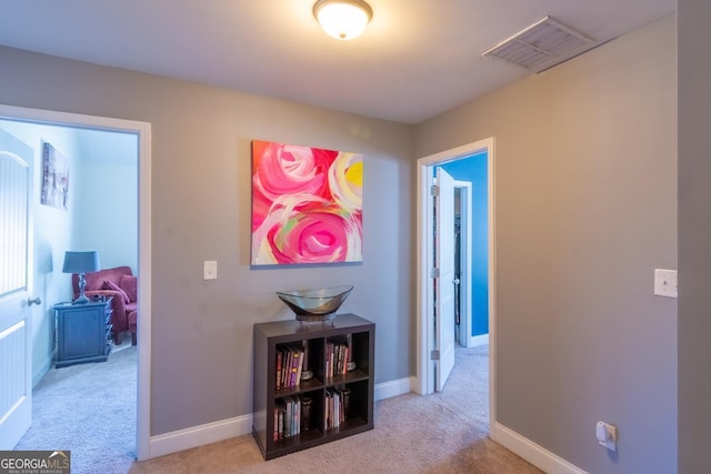 hallway featuring carpet floors, baseboards, and visible vents