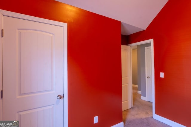 unfurnished bedroom with vaulted ceiling, carpet flooring, and baseboards