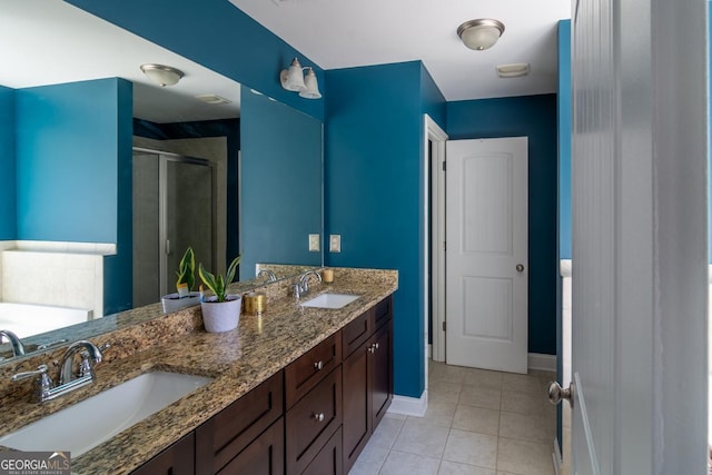 bathroom with tile patterned flooring, a shower stall, baseboards, and a sink