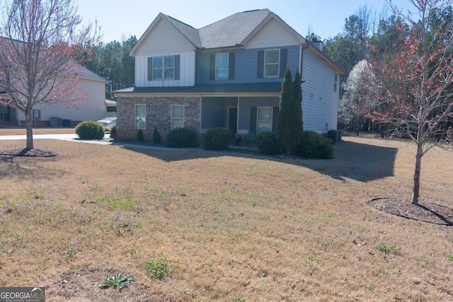 traditional-style home with central AC unit, stone siding, covered porch, board and batten siding, and a front yard