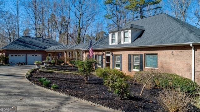 view of front facade with brick siding, driveway, an attached garage, and roof with shingles