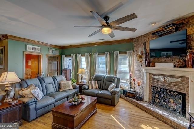 living room featuring ornamental molding, ceiling fan, light wood finished floors, and a fireplace