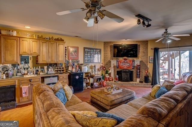 living area featuring a brick fireplace and a ceiling fan