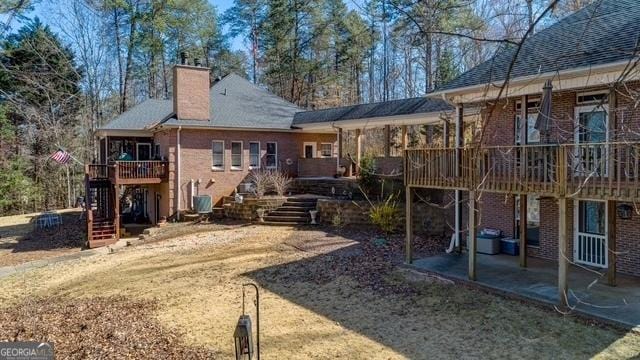 rear view of house with a patio area, stairs, a chimney, and brick siding