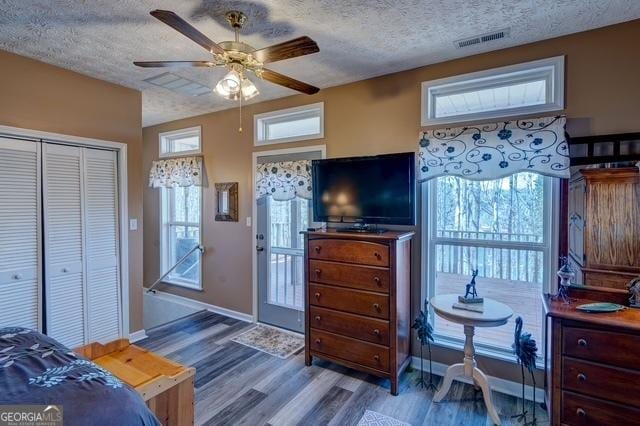 bedroom with a closet, visible vents, a textured ceiling, and wood finished floors