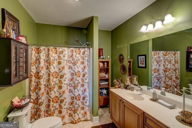 bathroom featuring toilet, curtained shower, tile patterned flooring, and vanity