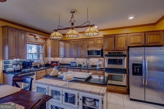 kitchen with stainless steel appliances, a sink, ornamental molding, backsplash, and tile counters