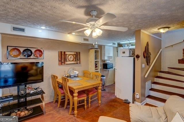 dining area featuring a ceiling fan, visible vents, a textured ceiling, and stairs