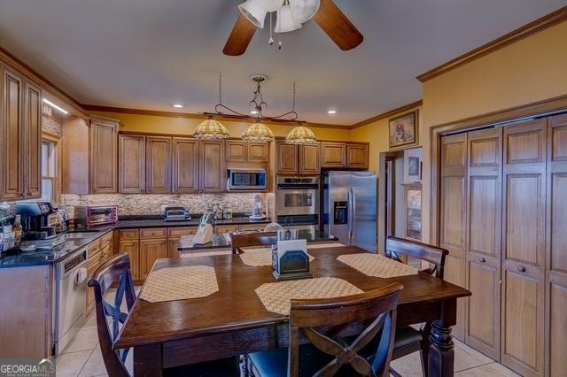 kitchen with light tile patterned floors, appliances with stainless steel finishes, dark countertops, and tasteful backsplash