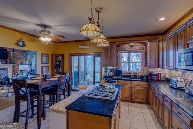 kitchen featuring stainless steel appliances, ornamental molding, backsplash, a center island, and dark countertops