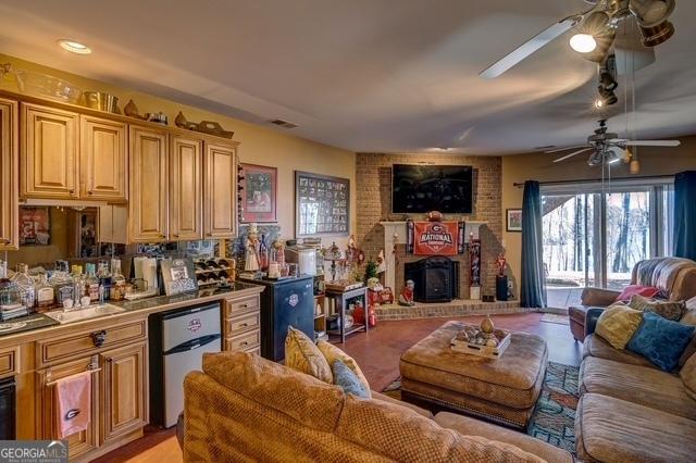 living room featuring a wood stove, visible vents, and a ceiling fan