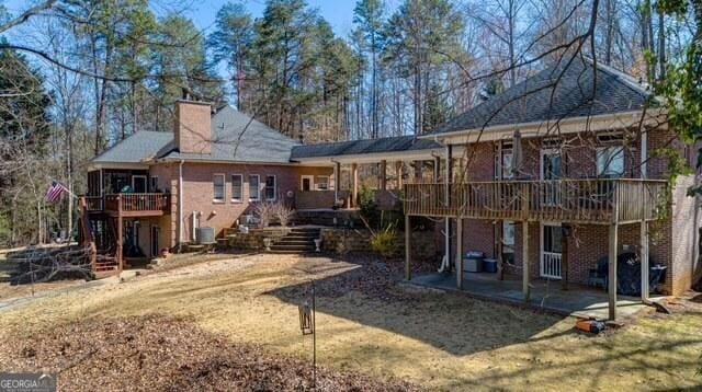 back of house with a patio, brick siding, stairs, a wooden deck, and a chimney