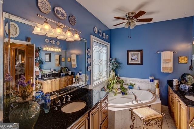 bathroom featuring two vanities, a sink, a bath, and tile patterned floors