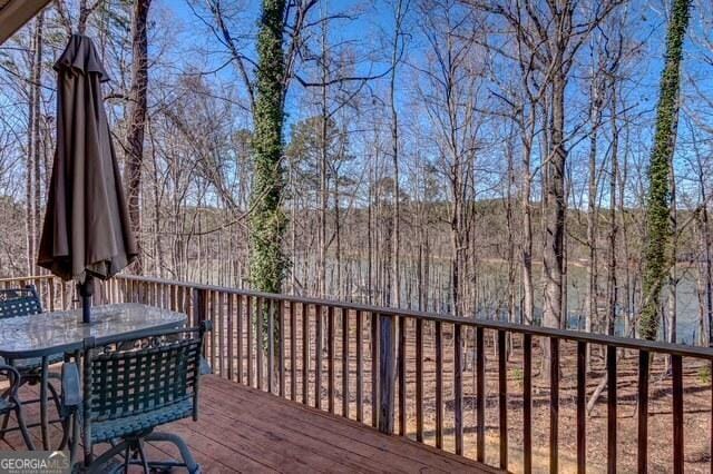 deck with outdoor dining area and a view of trees