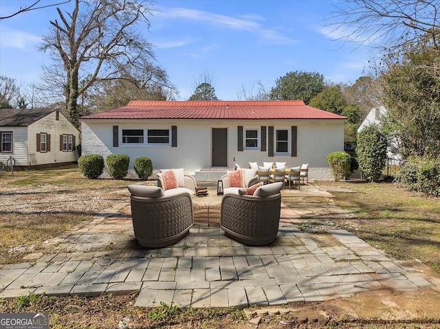 rear view of property featuring outdoor lounge area, metal roof, and a patio