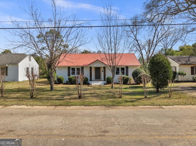 view of front of home with metal roof and a front lawn