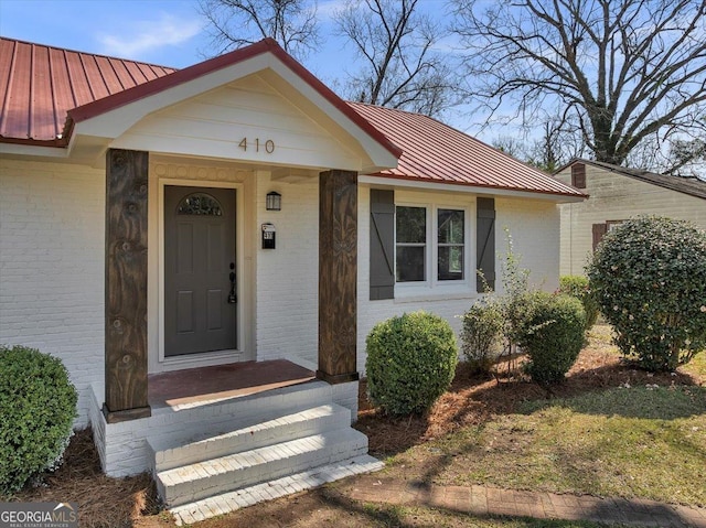 view of front of house with a standing seam roof, metal roof, and brick siding