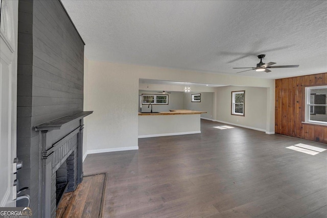 unfurnished living room with wood walls, a fireplace, dark wood-style floors, and a sink