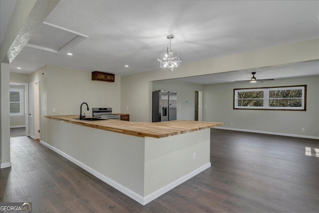 kitchen featuring a sink, wood counters, baseboards, appliances with stainless steel finishes, and dark wood-style floors