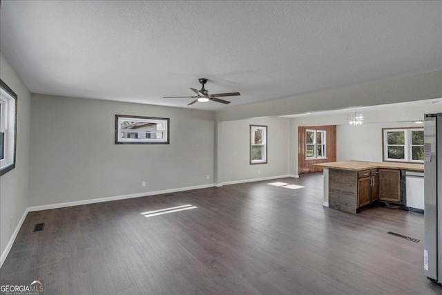 unfurnished living room with a textured ceiling, dark wood-style flooring, and visible vents