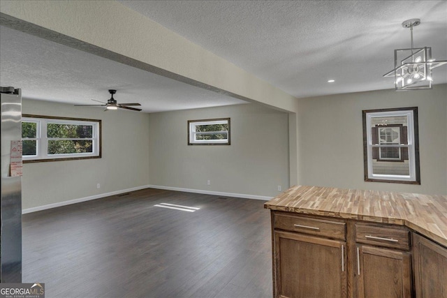 unfurnished living room with a ceiling fan, dark wood-style flooring, a textured ceiling, and baseboards