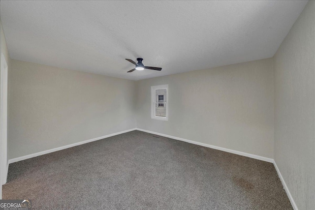 empty room with ceiling fan, dark colored carpet, a textured ceiling, and baseboards