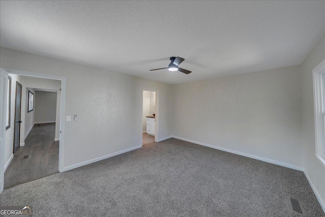 unfurnished bedroom with carpet, visible vents, a textured ceiling, and baseboards