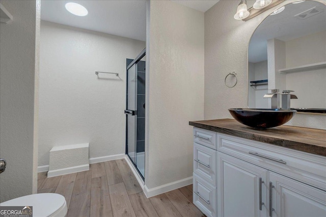 full bathroom with baseboards, a shower stall, visible vents, and wood finished floors