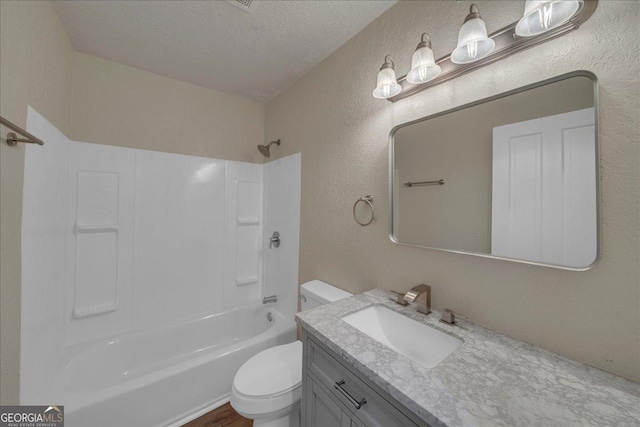 bathroom featuring a textured wall, vanity, toilet, and a textured ceiling