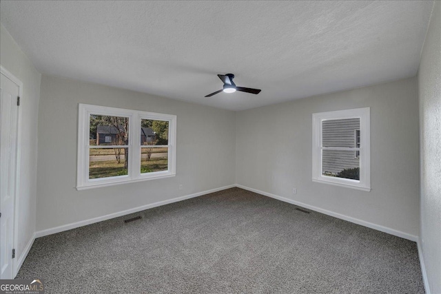 unfurnished room featuring dark colored carpet, visible vents, a ceiling fan, a textured ceiling, and baseboards