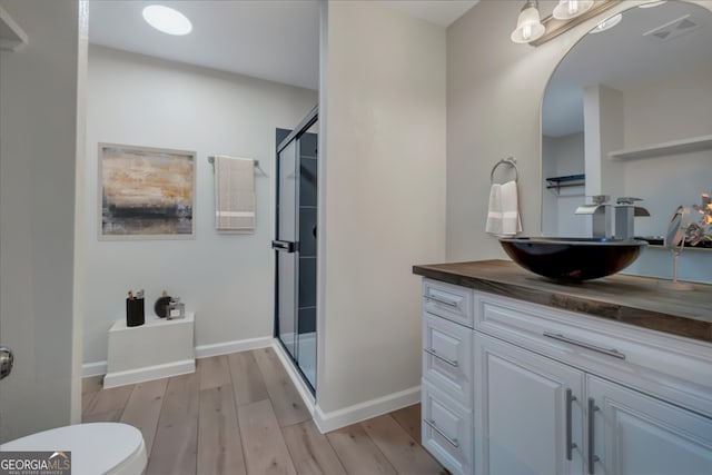 bathroom featuring visible vents, a shower stall, toilet, and wood finished floors