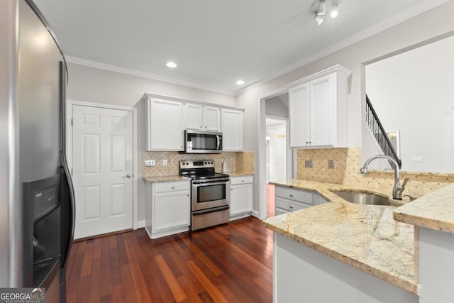 kitchen featuring dark wood-style flooring, stainless steel appliances, a sink, light stone countertops, and a peninsula