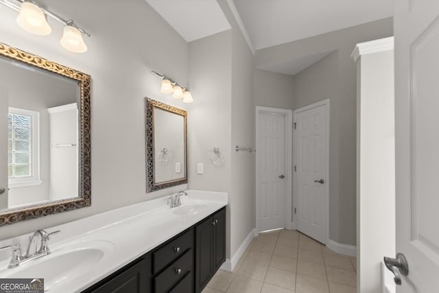 bathroom with double vanity, baseboards, a sink, and tile patterned floors