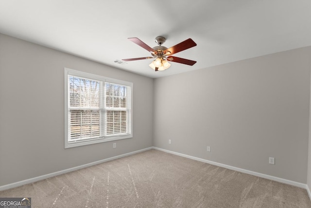 carpeted spare room with baseboards, visible vents, and ceiling fan