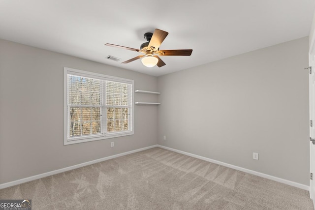 spare room with light carpet, baseboards, visible vents, and a ceiling fan