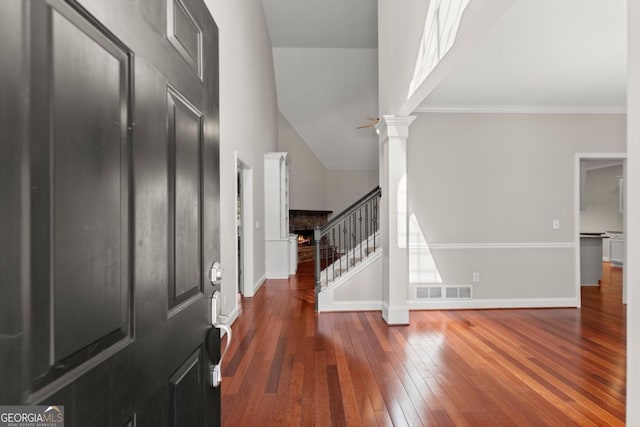 foyer entrance featuring wood-type flooring, visible vents, ornate columns, stairway, and baseboards