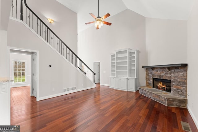 unfurnished living room featuring visible vents, a stone fireplace, hardwood / wood-style floors, and stairs