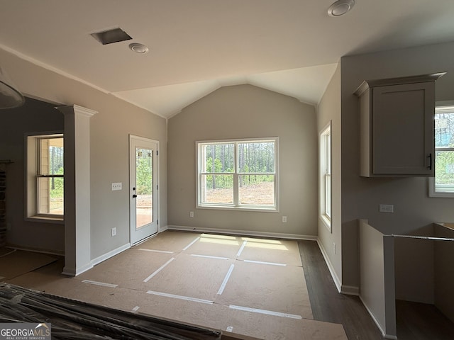 interior space with baseboards, wood finished floors, and vaulted ceiling