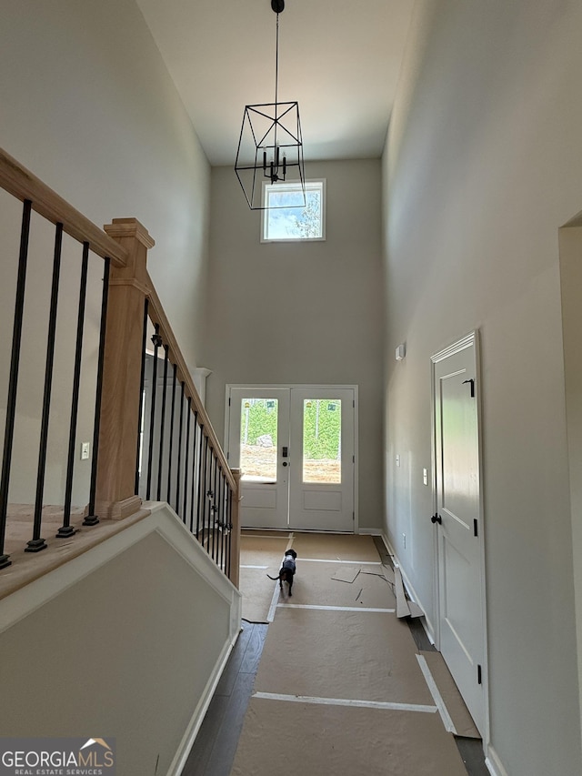 foyer entrance with a notable chandelier, french doors, baseboards, stairs, and a high ceiling