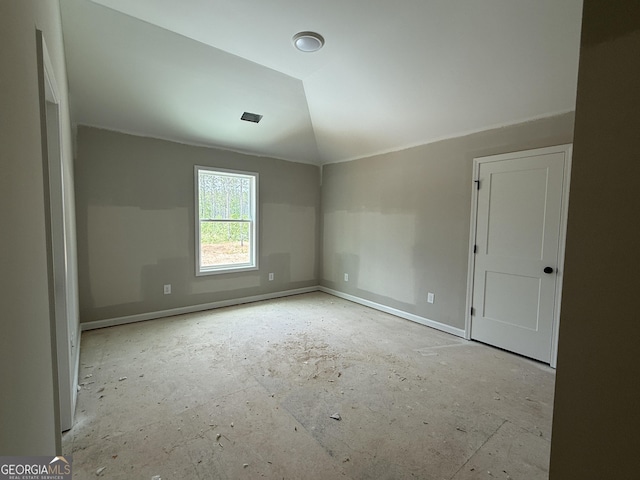 spare room with baseboards and vaulted ceiling