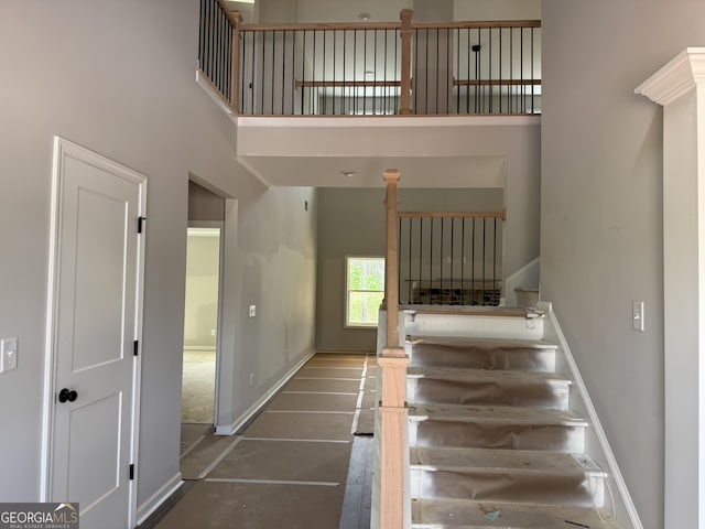 staircase featuring a high ceiling and baseboards