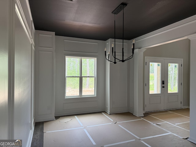 unfurnished dining area featuring a chandelier, baseboards, french doors, and a healthy amount of sunlight