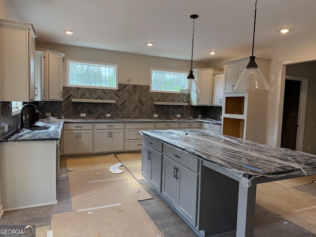 kitchen with tasteful backsplash, dark stone countertops, a sink, and gray cabinets